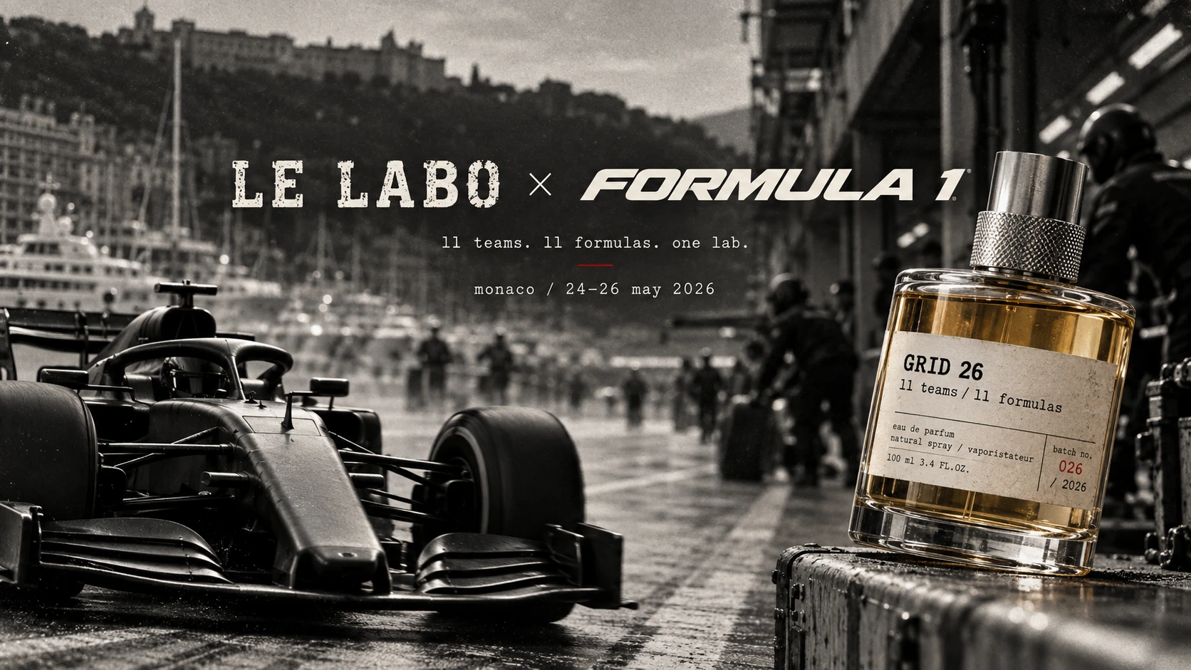 Le Labo × Formula 1. 11 teams. 11 formulas. One lab. Monaco, 24–26 May 2026. A moody black-and-white photo of a Formula 1 car front wing in the Monaco pit lane at dusk, with the hillside city and marina in the background and pit crew in the distance. A Grid 26 eau de parfum bottle, 100ml 3.4 fl.oz., batch no. 026/2026, rests on a weathered flight case in the foreground.